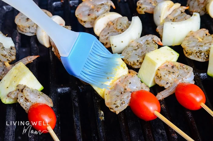 marinade being brushed onto shrimp kabobs on the grill