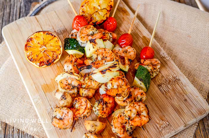 Wooden tray of lemon garlic shrimp skewers and veggies