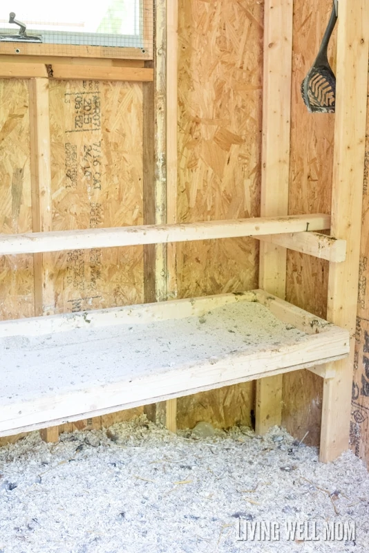 inside of a wooden chicken coop with a dropping board