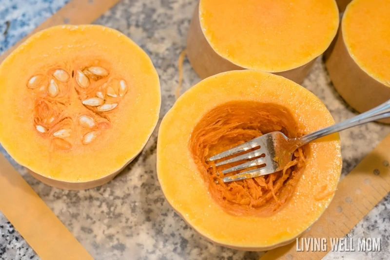 A fork being used to scrape the seeds out of pieces of squash. 