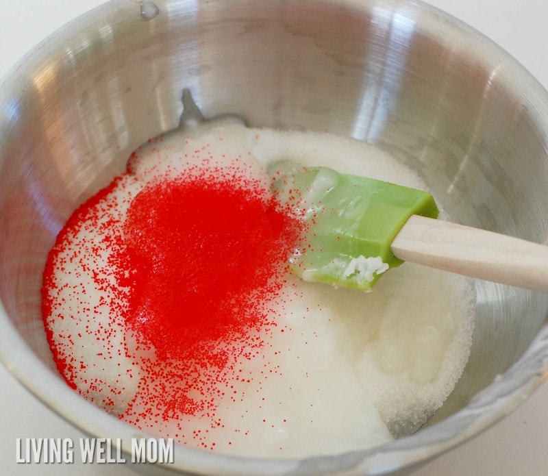 red jojoba beads being stirred into sugar scrub mixture
