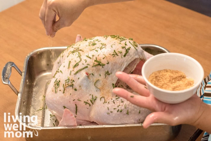 herb infused butter being applied to raw turkey