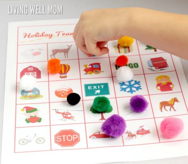 a child placing a pom pom marker on a square of a car bingo printable