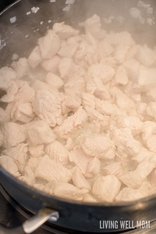 A pan on a stove top cooking pieces of chopped turkey breast.