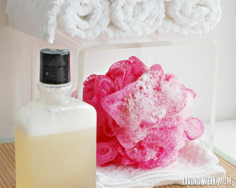 pink loofah with suds, rolled washclothes, and plastic bottle with homemade body wash