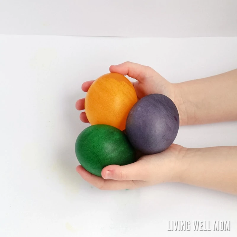 child holding 3 dyed rubber eggs (spring STEM activitiy)