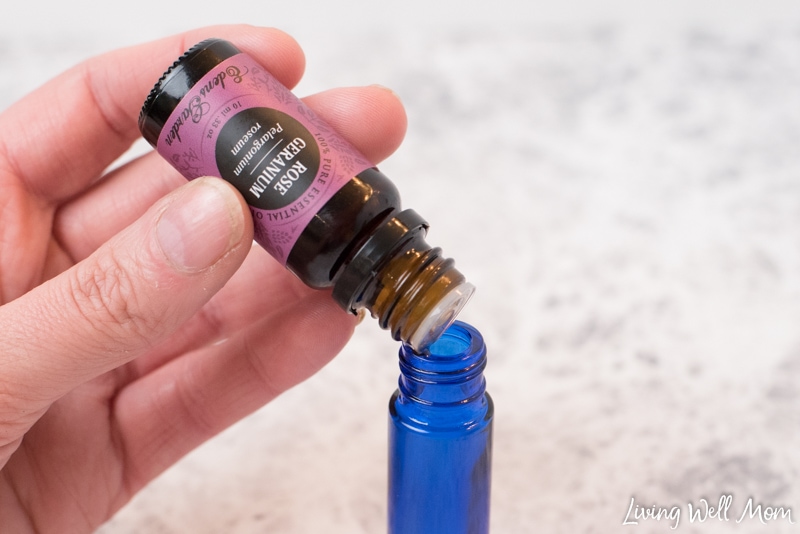 rose geranium essential oil dropping into blue glass roller bottle