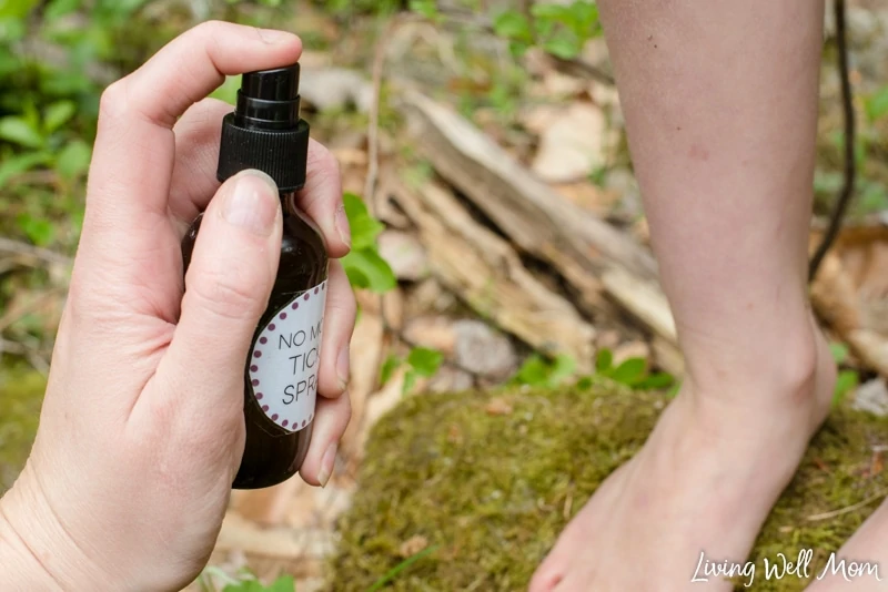 spraying no more ticks spray onto leg with woods background moss leaves