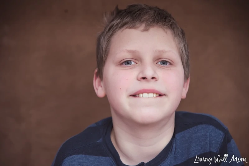 A young boy wearing a blue shirt and smiling at the camera