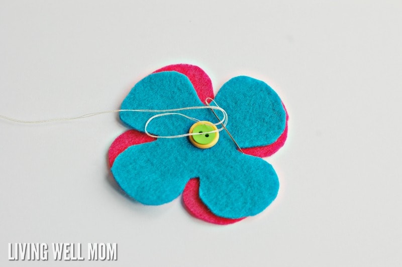 blue and pink felt flowers and a button sewn together with thread