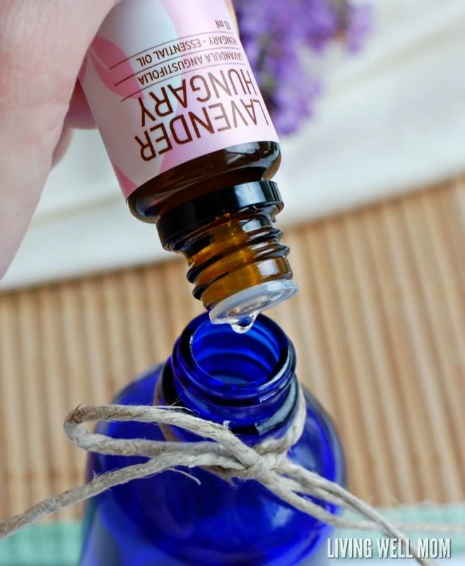 adding lavender essential oil to a blue glass bottle