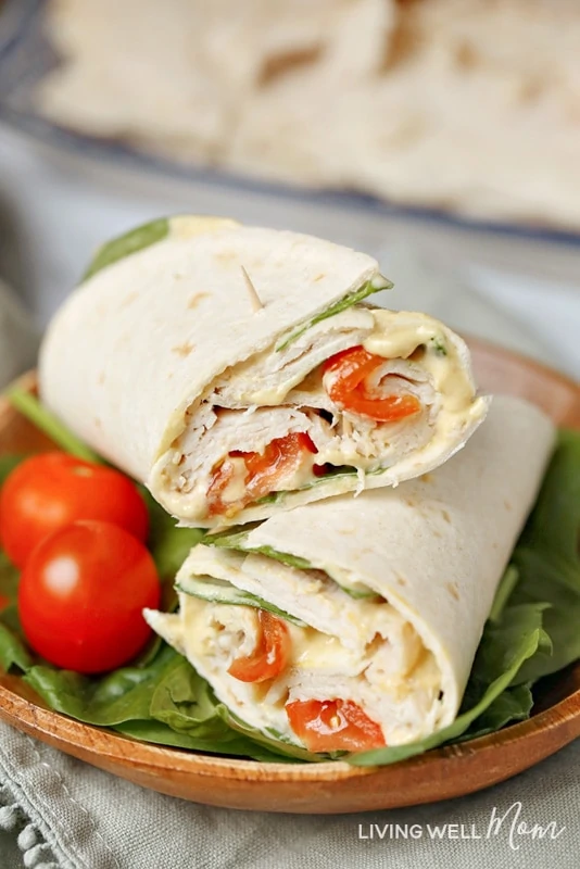 With delicious maple honey turkey slices, spinach, tomatoes, hummus, mayo, and Dijon mustard layered in a wrap, this Healthy Spinach Turkey Wrap is as satisfying and filling as it is tasty. It's a delicious, good-for-you alternative to the boring sandwiches or other common lunches we often eat. #healthyrecipes #lunch #easyrecipe