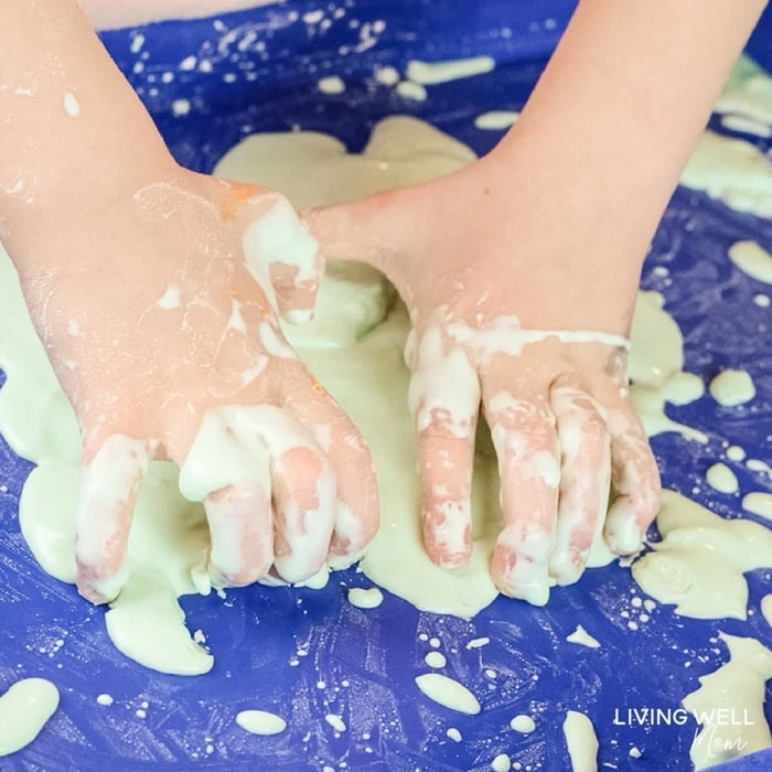 child's hand playing with oobleck slime