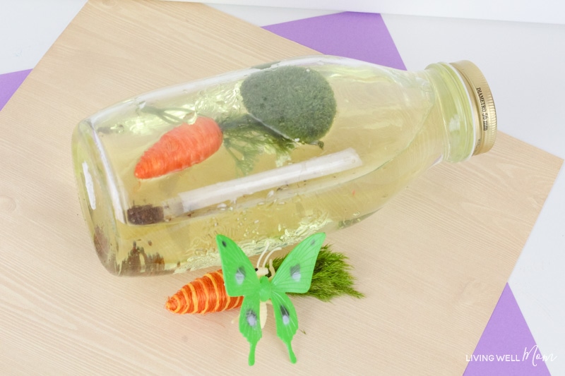 A bottle laid on it's side filled with sensory items representing the spring season. 