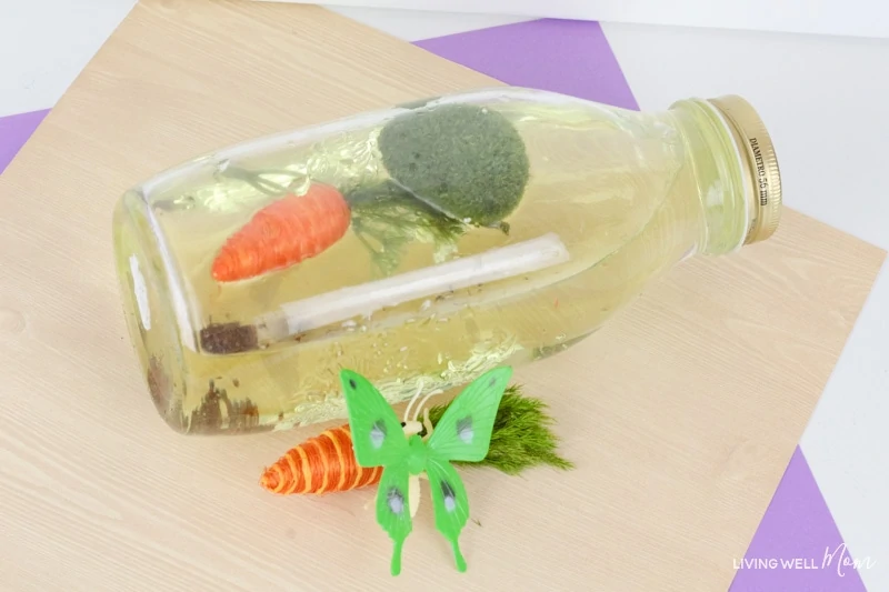 A bottle laid on it's side filled with sensory items representing the spring season. 