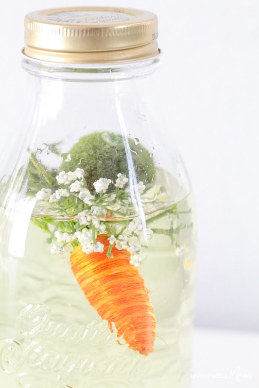 A bottle full of water and spring themed items with the lid glued shut. 