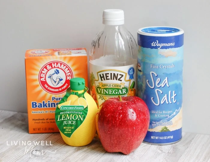 Produce wash ingredients - baking soda, vinegar, salt, and lemon juice next to an apple.
