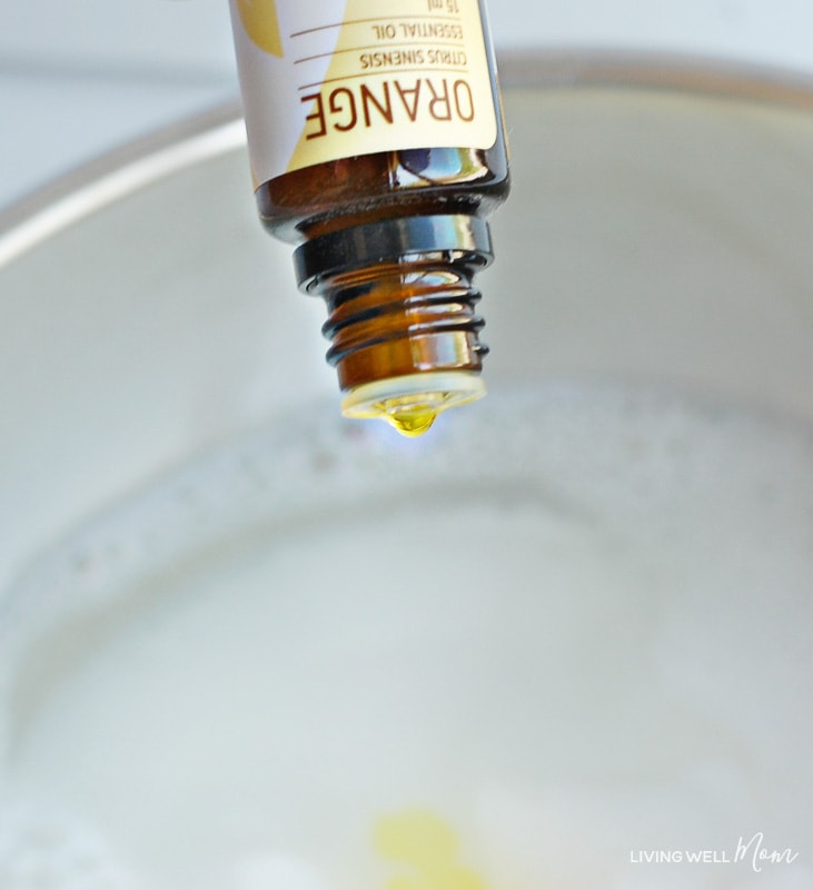 Drops of orange essential oil being added into mixture for garbage disposal cleaner. 