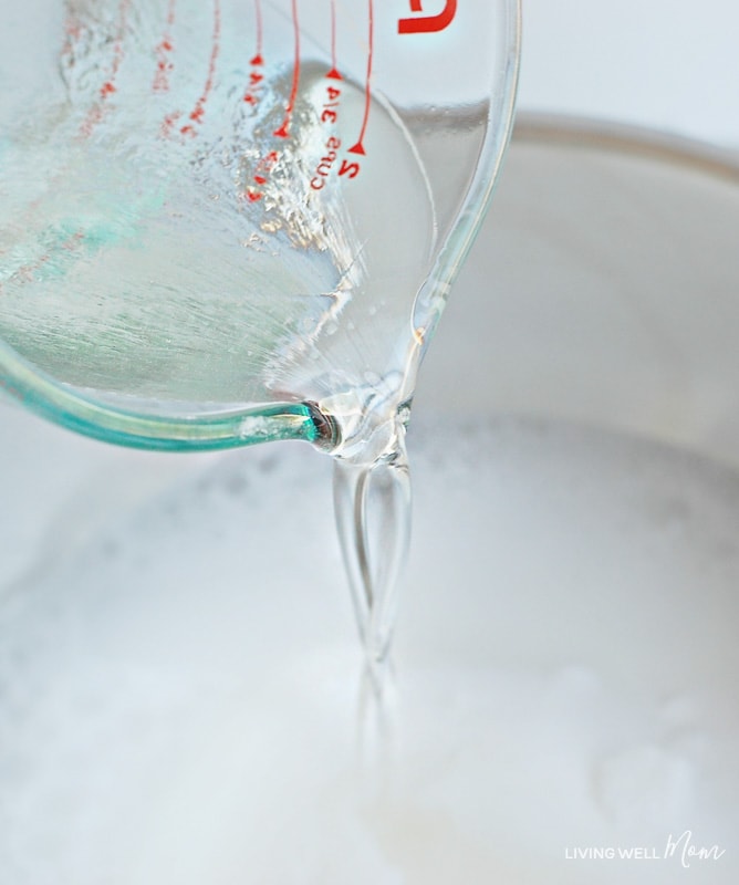 Soap and water mixture being poured into dry ingredients of deodorizing powder. 