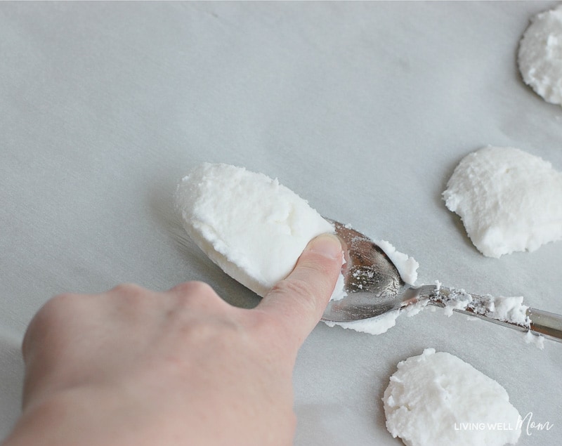 Spoon fulls of homemade disposal cleaner placed onto lined baking sheet. 