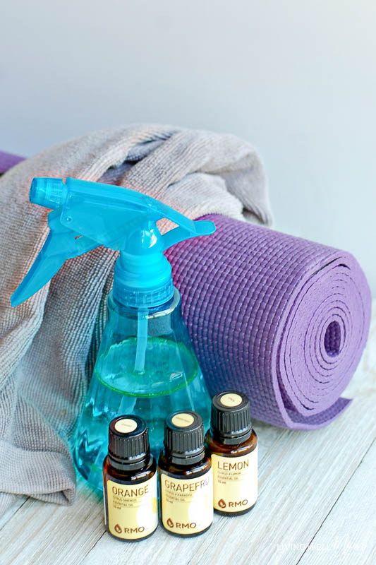 A blue spray bottle of DIY yoga mat spray made with orange, grapefruit and lemon essential oils. 