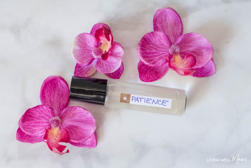 A roller of essential oils for patience, and three pink flowers. 
