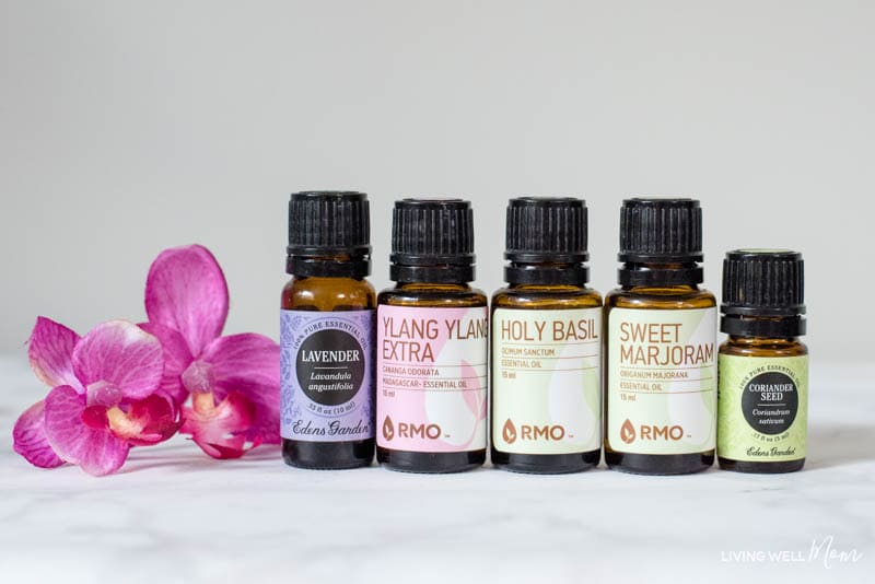 Bottles of calming essential oils next to a pink flower. 