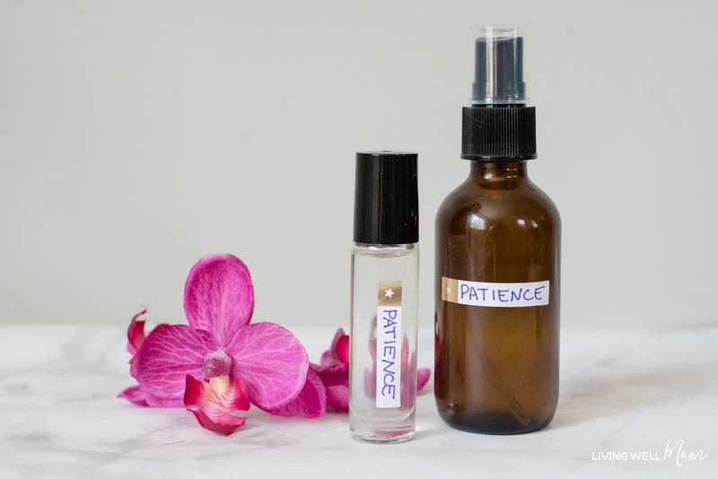 A glass spray bottle and roller bottle filled with DIY essential oil blend for moms. 
