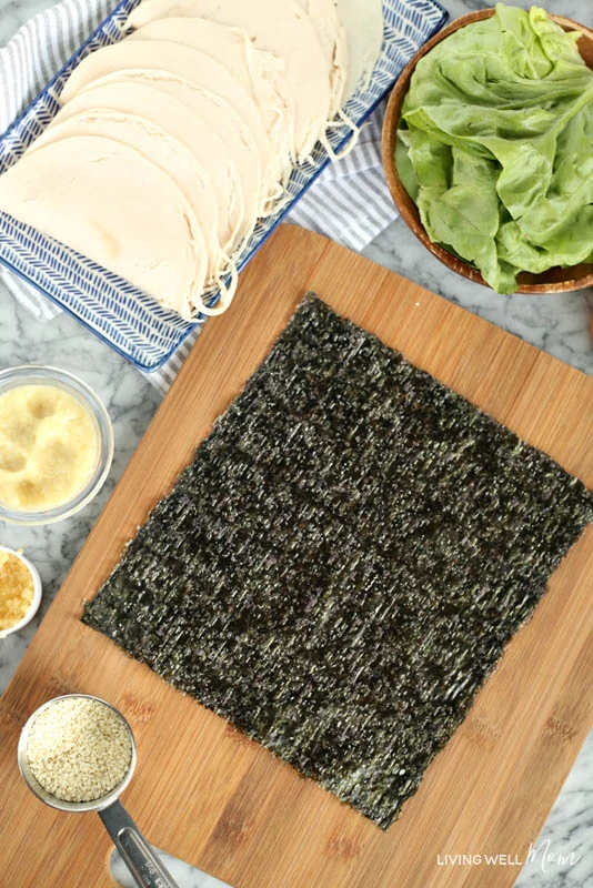 A bowl of food on a wooden cutting board, with dry seaweed and Sesame