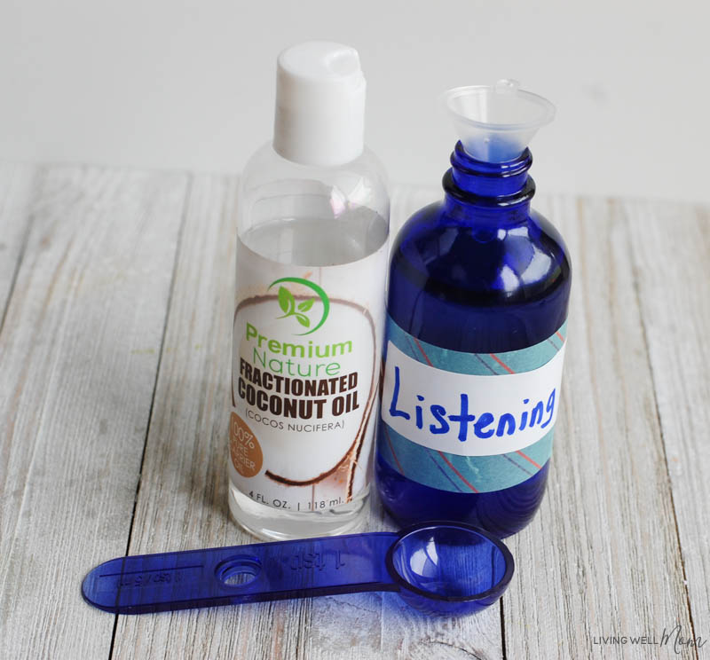 A close up of fractionated coconut oil and an essential oil spray bottle with the word listening taped on to it 