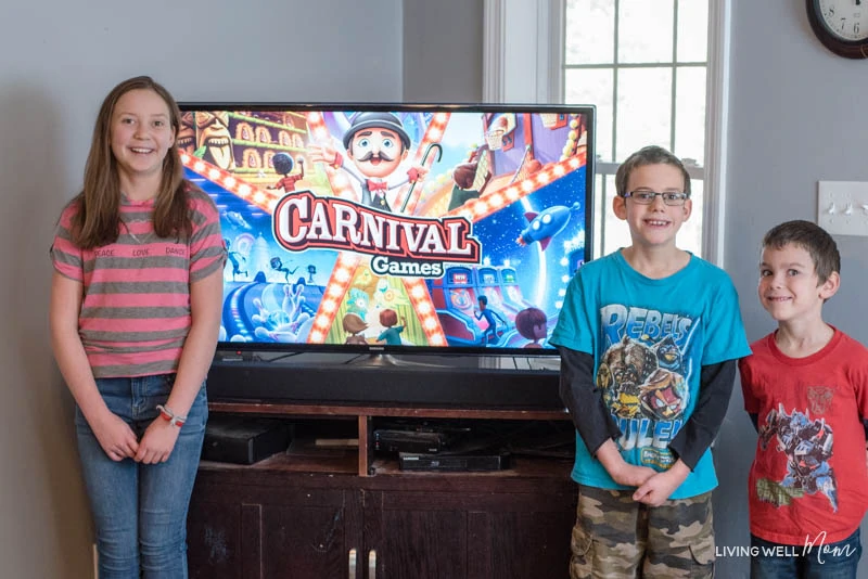  a boy and a girl standing in front of a tv with a Nintendo Switch Carnival game on it 