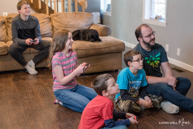 A group of people sitting around a living room playing a video game