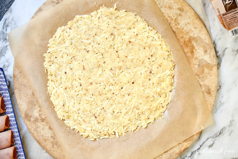 Cauliflower pizza crust mixture flattened into a circle on a parchment lined pizza pan. 