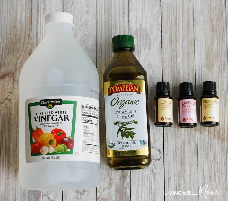 vinegar, olive oil, and essential oils laid flat on a counter for DIY dusting spray recipe