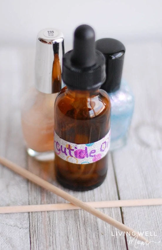 bottle of homemade cuticle oil with nail sticks and nail polish
