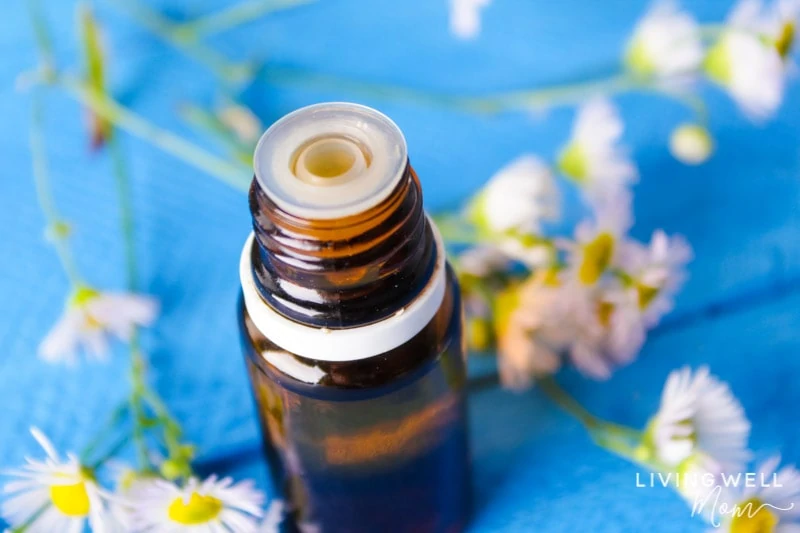 bottle of essential oil for allergies on blue table with flowers