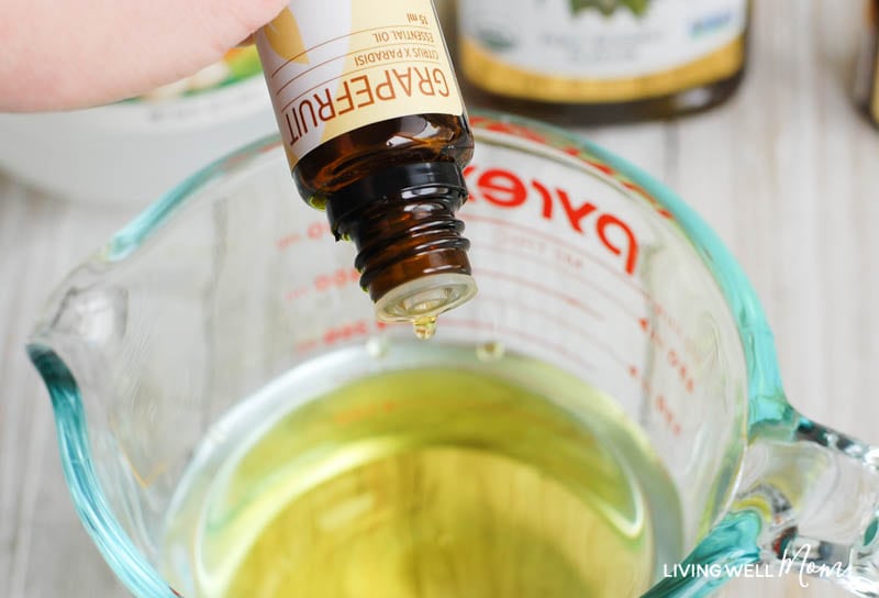 adding essential oils to a glass measuring jar to make a homemade dusting spray