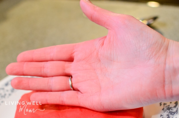 The palm of a person's hand next to red colored playdough.