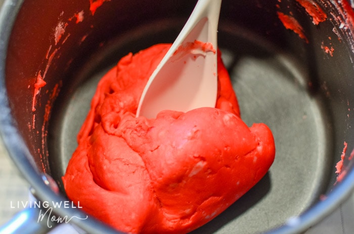 Sticky, red DIY playdough being cooked a little longer on the stove. 