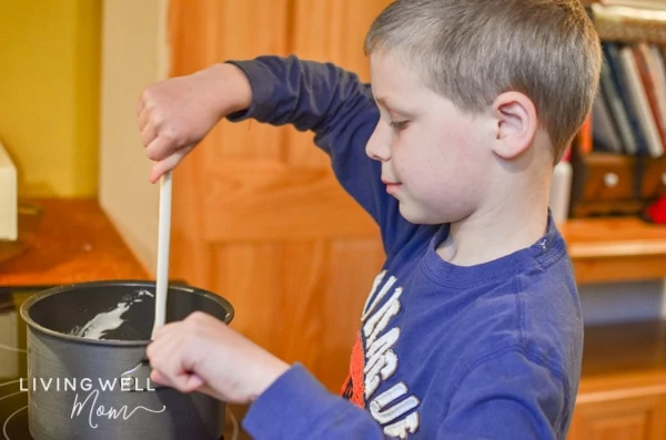 A kid helping to stir homemade playdough. 