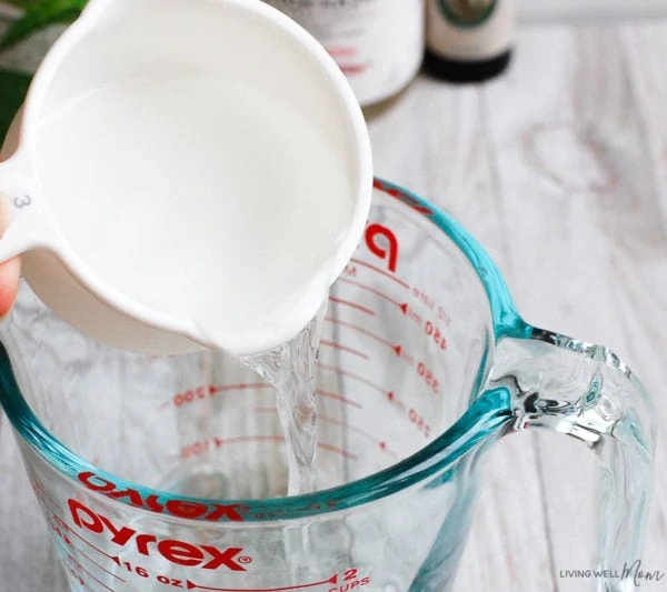 pouring ingredients into glass measuring cup for DIY face toner recipe