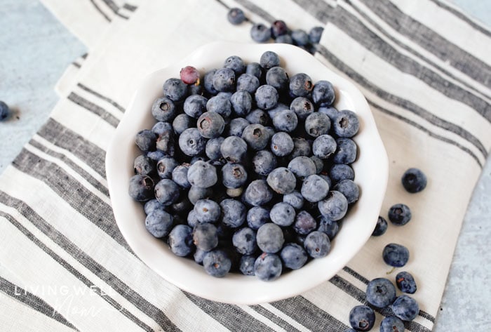 A bowl of fresh blueberries on a table. 