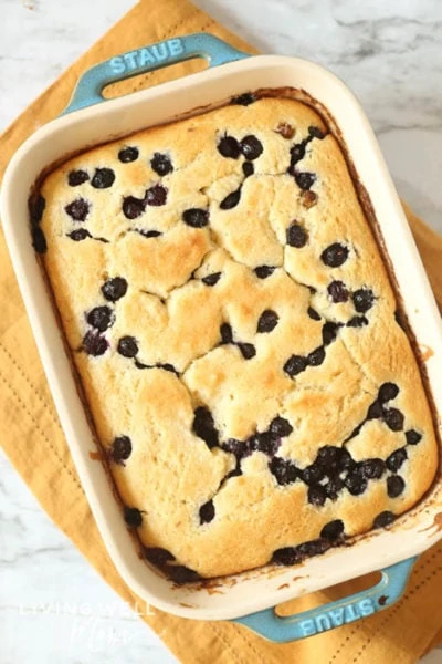 Freshly baked blueberry cake with fresh berries in a white baking dish. 