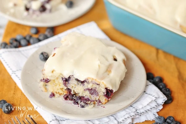 A slice of blueberry dump cake with cream cheese icing spread on top. 