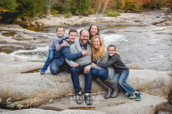 the Bragdon Family posing for a picture on some rocks in a river 