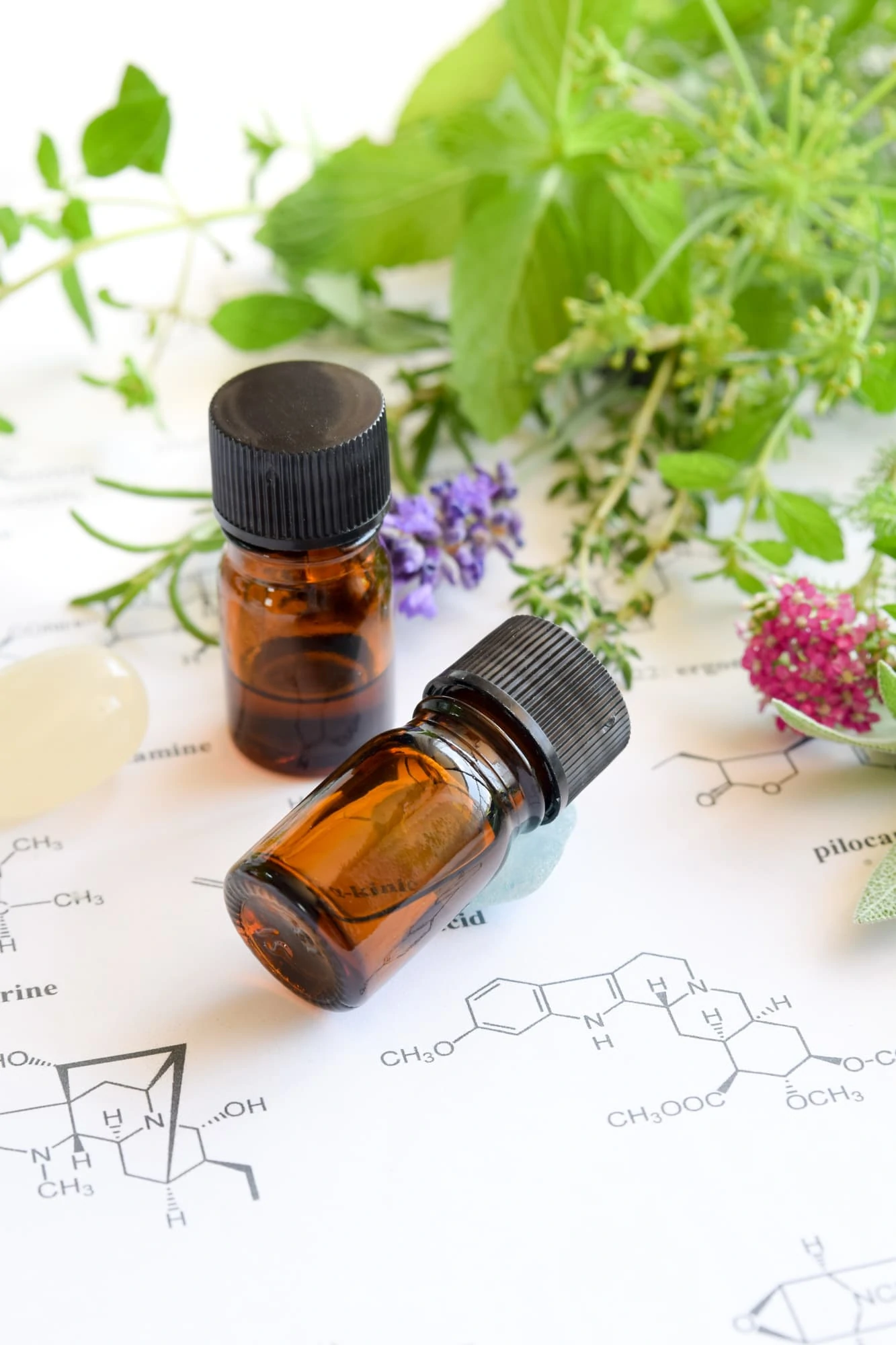 small brown essential oil bottles on paper with chemistry and plants