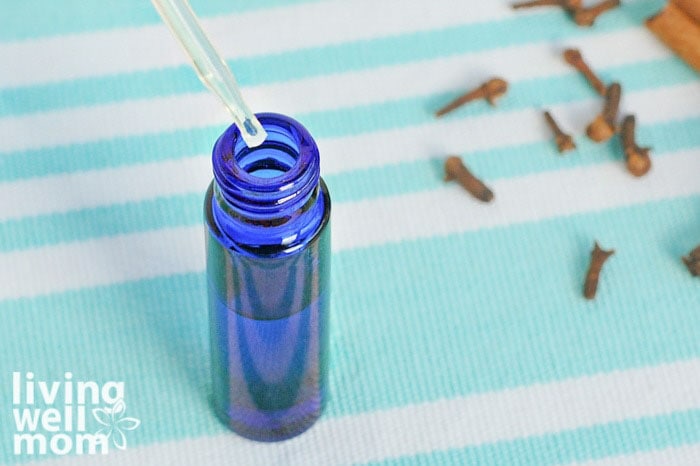 adding oil to small blue bottle with dropper