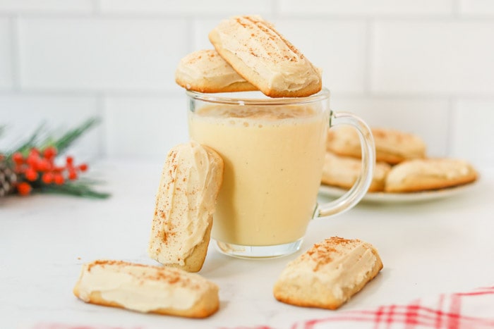 A glass mug of eggnog topped with cookies