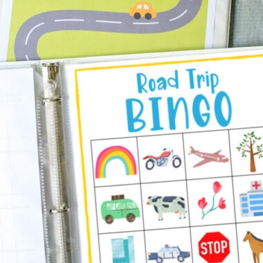 printed road trip bingo game in white binder with green travel binder behind