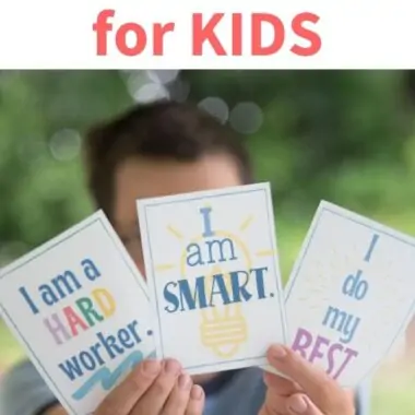 child holding up affirmation cards